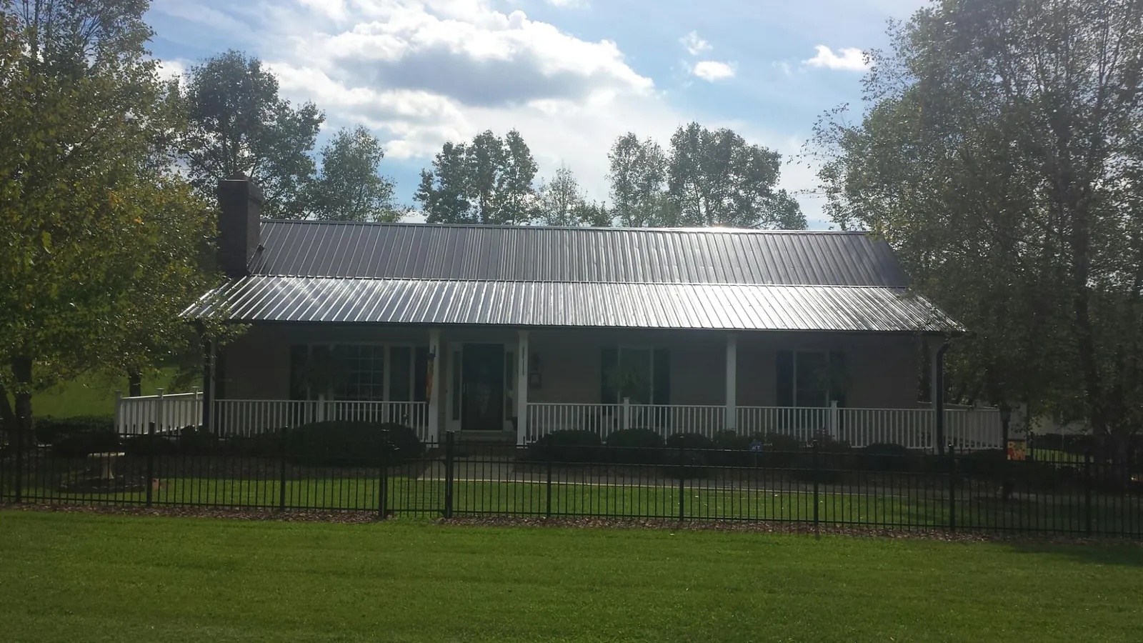 Gray metal roof on a brick ranch with a full width front porch — Gutter Guard Installation work by our crew in Stroudsburg