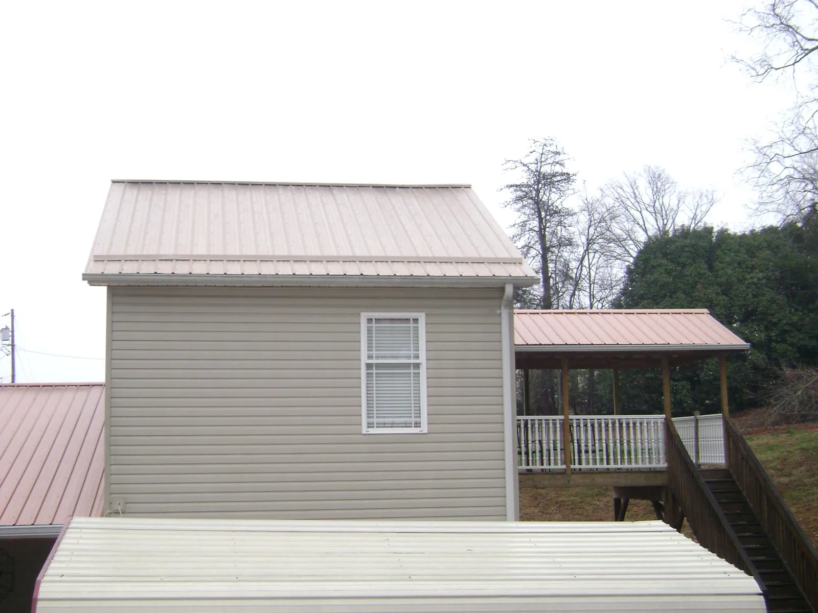 Tan metal roofs on a two story addition and attached porch, from a Roof Replacement job in Stroudsburg