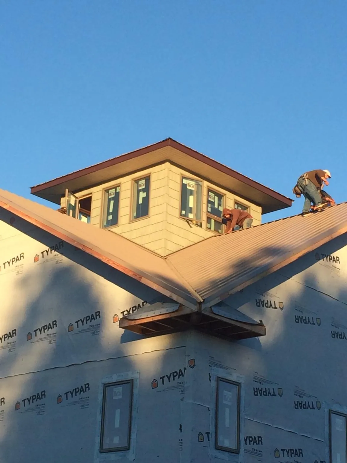Roofers working around a rooftop cupola on a new metal roof at sunset — Roof Waterproofing in Stroudsburg by Roofing Brothers
